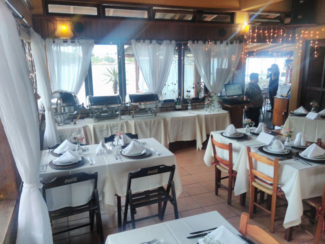 Salão do By Cuca preparado para evento com buffet e vista para o mar